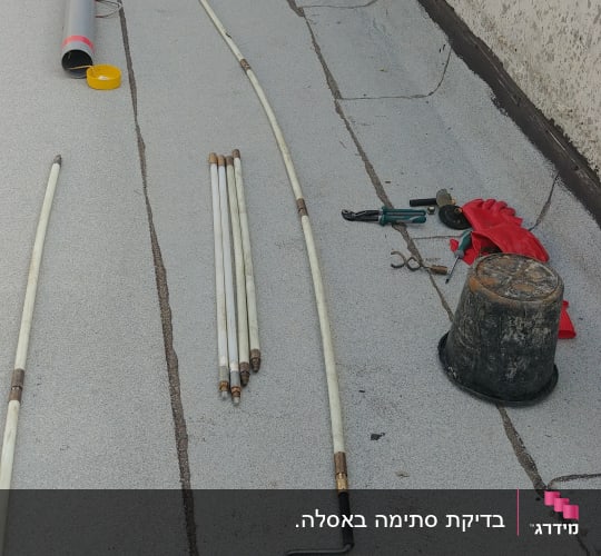 כלים וצינורות על גג, כולל דלי וכפפות אדומות